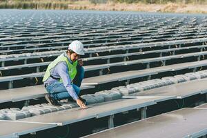 Engineer inspector holding laptop and working in solar panels power plant checking photovoltaic cells and electricity production. photo