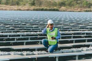 Engineer inspector holding laptop and working in solar panels power plant checking photovoltaic cells and electricity production. photo