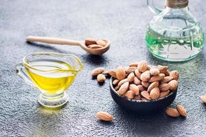 Fresco pelado Almendras en un cuenco y almendra petróleo en el mesa. un fuente de vitaminas y aceites natural productos cosméticos foto