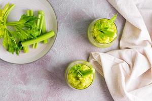 Fresh celery smoothie in glasses and cooking ingredients on the table. Vegetarian diet detox food. Top view photo