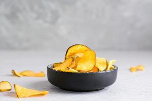 Appetizing sweet potato chips in a bowl on the table. Homemade snack. Copy space photo