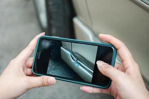 mujer utilizando un teléfono inteligente para tomando un foto a enviar a seguro. concepto de Reclamación seguro para un coche accidente en línea después enviar foto y evidencia a el seguro empresa