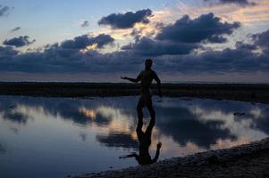 un masculino silueta y reflexión en el agua a oscuridad. foto