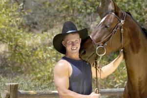 Handsome cowboy having a fun photo shoot with his horse.