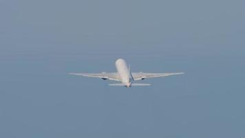 Widebody passenger airplane climb after takeoff, fly away, long shot. Airliner in the blue sky. Plane departure video