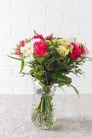 Beautiful large bouquet of bright flowers in a glass vase on a gray cement background. the concept of a holiday and a gift. photo