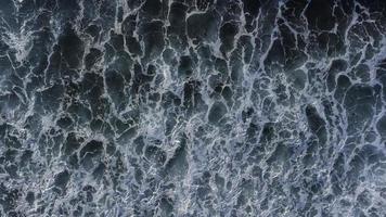 un impresionante ver de olas estrellarse a lo largo el playa, capturado desde un aéreo perspectiva. foto