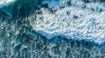 An awe-inspiring view of waves crashing along the beach, captured from an aerial perspective. photo