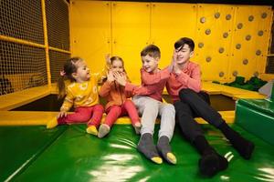 Kids together sit at playground park and give high five each other. Sisters and brothers in active entertaiments. photo