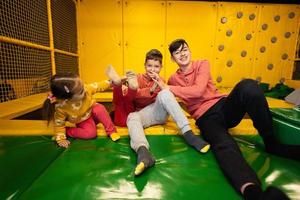 Kids together sit at playground park and give high five each other. Sisters and brothers in active entertaiments. photo