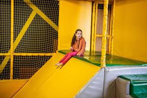 Little girl kid slide at yellow playground park. Child in active entertaiments. photo