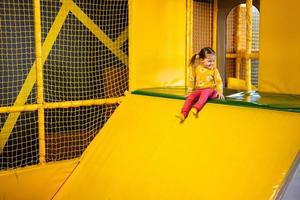 bebé niña niño diapositiva a amarillo patio de recreo parque. niño en activo entretenimientos foto