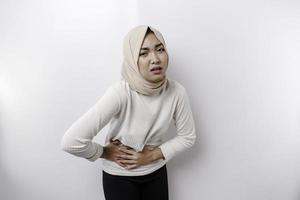 An Asian Muslim woman is fasting and hungry and touching her belly while looking aside thinking about what to eat photo