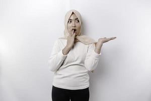 conmocionado asiático musulmán mujer señalando a el Copiar espacio en junto a su, aislado por blanco antecedentes foto
