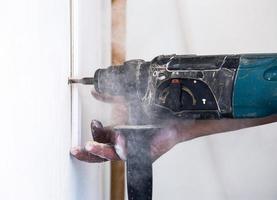 close up of electric drill making hole in a wall, repair, building and home concept photo