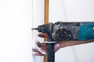 close up of electric drill making hole in a wall, repair, building and home concept photo
