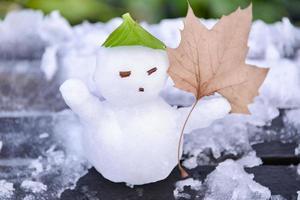 un pequeño nieve hombre con arce hoja foto