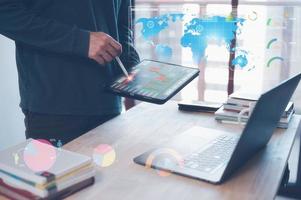 investment strategy data analysis concept, businessman analyse data from virtual graph and icon, man working with computer laptop and tablet on table in office. photo