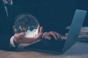 investment financial and saving concept, businessman holding virtual trading graph, working on computer laptop on table. photo
