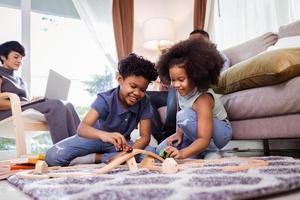 Happy America Africa Family, Son and Daughter play toy in living room with parents photo