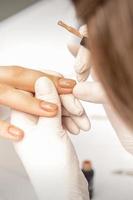 Manicurist applying beige nail polish photo