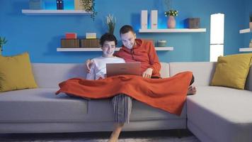 appy brothers watching comedy movies together at home using laptop, browsing social media. Younger brother and older brother watching movies on laptop late at night at home. video