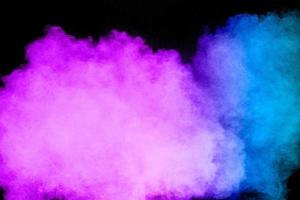 Launched blue pink dust particles splashing.Bizarre forms of blue pink powder explosion cloud on white background. photo