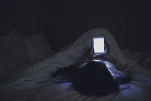 Asian woman playing game on smartphone in the bed at night,Thailand people,Addict social media photo