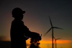 Asian Man engineers working and holding the report at wind turbine farm Power Generator Station on mountain,Thailand people,Technician man at site of work photo