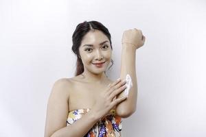 Skin Care Products Concept. Asian woman applying moisturizing lotion on body after shower, standing wrapped in towel, cropped image photo