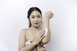 Skin Care Products Concept. Asian woman applying moisturizing lotion on body after shower, standing wrapped in towel, cropped image photo