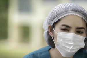 Tired depressed female asian scrub nurse wears face mask blue uniform sits on hospital floor,Young woman doctor stressed from hard work photo