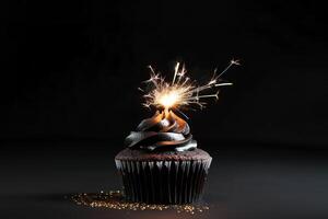 Elegant black cupcake with glitter, sparkler and copy space on black background. Happy Birthday dessert. Empty space for text. Postcard, greeting card design. . photo