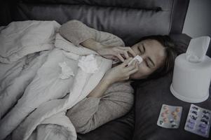 Asian sick woman sit on the sofa stay at home,The woman felt bad, wanted to lie down and rest,high fever photo