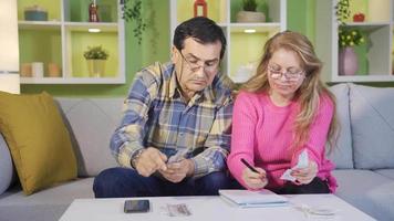 Worried retired couple calculating bills checking bank loan payment paying unpaid debt taxes. video