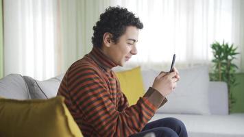 Fun and happy boy using smartphone at home. Boy alone at home, texting on his smartphone, using social media, inappropriate sites. video