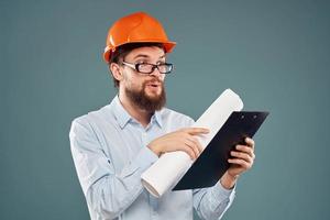 man in orange hard hat blueprints in hands construction industry blue background photo