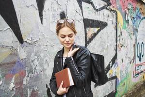 woman in leather jacket near graffiti on the wall in the street photo