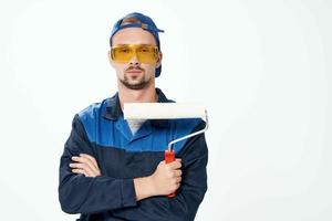 un hombre en un trabajando uniforme un rodillo para pintura paredes en su manos decoración reparar foto