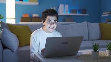 Boy using laptop with excitement and aggression. Boy is using laptop with excitement and anger at home, playing video game, watching football match, watching boxing match.