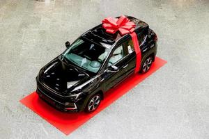 negro nuevo brillante coche con juguete polar osos en el salón envuelto con grua regalo arco foto