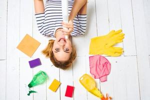 woman in striped t-shirt lies on the floor cleaning supplies detergent housework photo