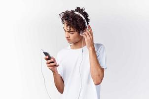 pelo rizado chico en blanco camiseta con auriculares música tecnología entretenimiento foto