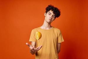 guy with curly hair oranges in hands fruit red background photo