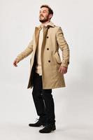 a man in a beige coat and trousers on a Light background boots Copy Space photo