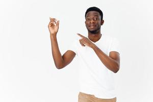 handsome guy of African appearance shows a finger to the side on a light background and beige trousers photo