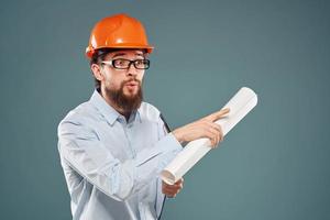 Male engineer professional orange hard hat safety construction blueprints in hands photo