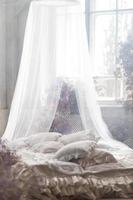 un cama en un brillante dormitorio en pastel colores en boho estilo, el tendencias color de 2023. el habitación es decorado con lila y rosado Gypsophila flores, Clásico decoración en el habitación en retro desván estilo. foto