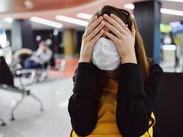 woman in medical mask covers her face with her hands fatigue flight delay airport photo