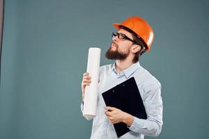 un masculino ingeniero en un naranja difícil sombrero con documentos en el manos de construcción dibujos foto